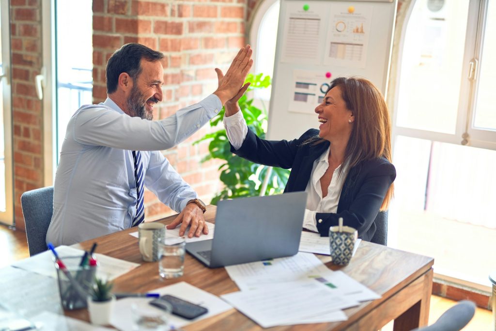 Upbeat business man and woman high-fiving one another